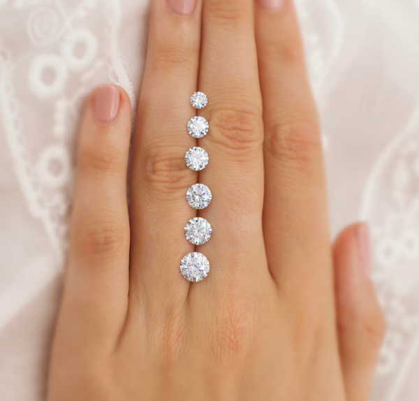 hand displaying loose diamonds of different sizes 
