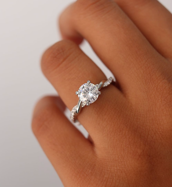 close up of hand wearing round lab diamond engagement ring with twisted platinum band
