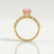 Allure solitaire engagement ring in 18k yellow gold with a round morganite-pink lab-grown sapphire centre stone, side profile showing the setting and band.