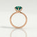 Annora twist solitaire engagement ring in 18k rose gold with a round lab-grown emerald centre stone, side profile showing the setting and band.
