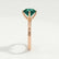 Annora twist solitaire engagement ring in 18k rose gold with a round lab-grown emerald centre stone, end-on view showing the setting and band.