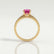 Catalina solitaire engagement ring in 18k yellow gold with a round pink lab-grown sapphire centre stone, side profile showing the setting and band.