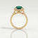 Cecily halo engagement ring in 18k yellow gold with a round lab-grown emerald centre stone and diamond accents, side profile showing the setting and band.