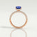 Coco hidden halo engagement ring in 18k rose gold with an elongated cushion blue lab-grown sapphire centre stone on a triple pavé band, side profile showing the setting and band.