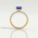 Coco hidden halo engagement ring in 18k yellow gold with an elongated cushion blue lab-grown sapphire centre stone on a triple pavé band, side profile showing the setting and band.