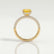 Coco hidden halo engagement ring in 18k yellow gold with an oval yellow lab-grown sapphire centre stone and diamond accents on a triple pavé band, side profile showing the setting and band.