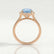 Darley halo engagement ring in 18k rose gold with an elongated cushion aquamarine-blue lab-grown sapphire centre stone, side profile showing the setting and band.