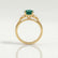 Delilah shoulder-set engagement ring in 18k yellow gold with a round lab-grown emerald centre stone, side profile showing the setting and band.