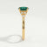 Delilah shoulder-set engagement ring in 18k yellow gold with a round lab-grown emerald centre stone, end-on view showing the setting and band.
