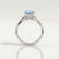 Eden vine solitaire engagement ring with a princess-cut aquamarine-blue lab-grown sapphire centre stone and diamond accents, side profile showing the setting and band.