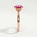 Elena solitaire engagement ring in 18k rose gold with a round pink lab-grown sapphire centre stone, end-on view showing the setting and band.