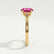 Elena solitaire engagement ring in 18k yellow gold with a round pink lab-grown sapphire centre stone, end-on view showing the setting and band.
