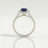 Esme halo engagement ring with an emerald-cut lab-grown alexandrite centre stone and diamond accents, side profile showing the setting and band.