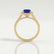 Esme halo engagement ring in 18k yellow gold with an emerald-cut blue lab-grown sapphire centre stone and diamond accents, side profile showing the setting and band.