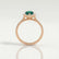 Harlow halo engagement ring in 18k rose gold with a pear-shaped lab-grown emerald centre stone and diamond accents, side profile showing the setting and band.