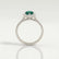 Harlow halo engagement ring in 18k white gold with a pear-shaped lab-grown emerald centre stone and diamond accents, side profile showing the setting and band.