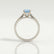 Isabella solitaire engagement ring in platinum with an oval aquamarine-blue lab-grown sapphire centre stone, end-on view showing the setting and band.