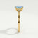 Isabella solitaire engagement ring in 18k yellow gold with an oval aquamarine-blue lab-grown sapphire centre stone, side profile showing the setting and band.