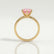 Juliet solitaire engagement ring in 18k yellow gold with a round morganite-pink lab-grown sapphire centre stone, side profile showing the setting and band.