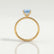 Lively hidden halo engagement ring in 18k yellow gold with a cushion aquamarine-blue lab-grown sapphire centre stone on a pavé-set band, side profile showing the setting and band.