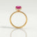 Lively hidden halo engagement ring in 18k yellow gold with an elongated cushion pink lab-grown sapphire centre stone on a pavé-set band, side profile showing the setting and band.