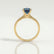Lottie solitaire engagement ring in 18k yellow gold with a round lab-grown alexandrite centre stone, side profile showing the setting and band.