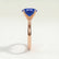 Lulu solitaire engagement ring in 18k rose gold with an elongated cushion blue lab-grown sapphire centre stone, end-on view showing the setting and band.