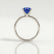 Lulu solitaire engagement ring in 18k white gold with an elongated cushion blue lab-grown sapphire centre stone, side profile showing the setting and band.