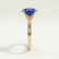 Lulu solitaire engagement ring in 18k yellow gold with an elongated cushion blue lab-grown sapphire centre stone, end-on view showing the setting and band.