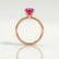 Lulu solitaire engagement ring in 18k rose gold with an elongated cushion pink lab-grown sapphire centre stone, side profile showing the setting and band.
