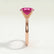 Lulu solitaire engagement ring in 18k rose gold with an elongated cushion pink lab-grown sapphire centre stone, end-on view showing the setting and band.