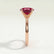 Lulu solitaire engagement ring in 18k rose gold with an elongated cushion lab-grown ruby centre stone, end-on view showing the setting and band.