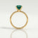 Lulu solitaire engagement ring in 18k yellow gold with a cushion lab-grown emerald centre stone, side profile showing the setting and band.