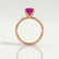 Lulu solitaire engagement ring in 18k rose gold with an emerald-cut pink lab-grown sapphire centre stone, side profile showing the setting and band.