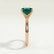 Lulu solitaire engagement ring in 18k rose gold with a radiant lab-grown emerald centre stone, end-on view showing the setting and band.