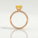 Lulu solitaire engagement ring in 18k rose gold with a radiant yellow lab-grown sapphire centre stone, side profile showing the setting and band.