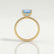 Macy shoulder-set engagement ring in 18k yellow gold with a princess-cut aquamarine-blue lab-grown sapphire centre stone, side profile showing the setting and band.