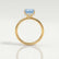 Paris hidden halo engagement ring in 18k yellow gold with a princess-cut aquamarine-blue lab-grown sapphire centre stone and diamond accents, side profile showing the setting and band.