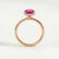 Paris hidden halo engagement ring in 18k rose gold with a round pink lab-grown sapphire centre stone and diamond accents, side profile showing the setting and band.