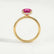 Paris hidden halo engagement ring in 18k yellow gold with a round pink lab-grown sapphire centre stone and diamond accents, side profile showing the setting and band.