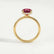 Paris hidden halo engagement ring in 18k yellow gold with a round lab-grown ruby centre stone and diamond accents, side profile showing the setting and band.