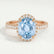 Rosa halo engagement ring in 18k rose gold with an oval aquamarine-blue lab-grown sapphire centre stone and diamond accents, front view.