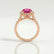 Rosa halo engagement ring in 18k rose gold with an oval pink lab-grown sapphire centre stone and diamond accents, side profile showing the setting and band.