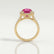 Rosa halo engagement ring in 18k yellow gold with an oval pink lab-grown sapphire centre stone and diamond accents, side profile showing the setting and band.