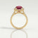 Rosa halo engagement ring in 18k yellow gold with an oval lab-grown ruby centre stone and diamond accents, side profile showing the setting and band.