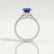 Viola shoulder-set engagement ring in platinum with an oval blue lab-grown sapphire centre stone and diamond accents, side profile showing the setting and band.