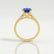Viola shoulder-set engagement ring in 18k yellow gold with an oval blue lab-grown sapphire centre stone and diamond accents, side profile showing the setting and band.