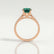 Viola shoulder-set engagement ring in 18k rose gold with an oval lab-grown emerald centre stone and diamond accents, side profile showing the setting and band.