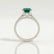 Viola shoulder-set engagement ring in platinum with an oval lab-grown emerald centre stone and diamond accents, side profile showing the setting and band.