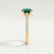 Viola shoulder-set engagement ring in 18k yellow gold with an oval lab-grown emerald centre stone and diamond accents, end-on view showing the setting and band.